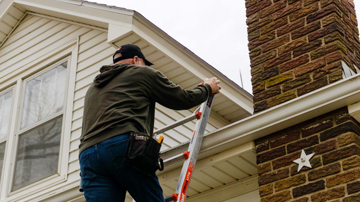 Dan getting on a roof of a house